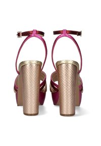 Sandalias de tacón alto en rosa y dorado con un tacón de bloque dorado texturizado y una delgada correa en el tobillo, con una parte superior rosa lisa y un diseño de espalda abierta.