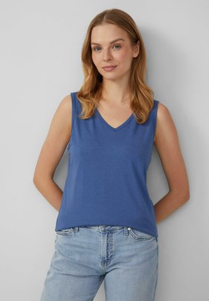 Blauwe mouwloze top met een V-hals, gemaakt van een gladde stof. Het heeft een ontspannen pasvorm en is gecombineerd met lichtblauwe jeans.