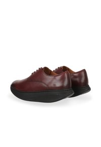 Zapatos de cuero en burdeos oscuro con suelas de goma negras. Diseño de punta redondeada, acabado suave y detalle de costura sutil. Cierre con cordones.