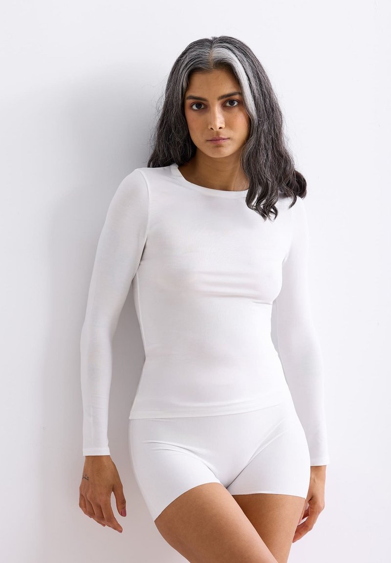 White long-sleeve top and short bottoms made of smooth, stretchy material. Fitted design with a round neckline and seamless construction.