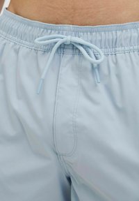 Lichtblauwe zwembroek met een elastische tailleband en trekkoord. Glad materiaal, met een zijnaaddetail en subtiele stiksels.