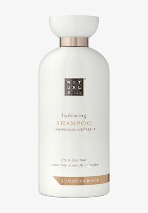 Shampoo idratante in una bottiglia bianca opaca con forma arrotondata, hardware in argento e testo dorato. Adatto per capelli secchi e opachi.