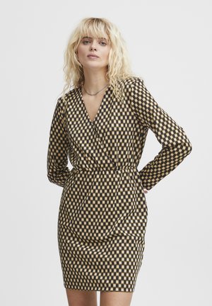 Abito a scacchi in nero e beige con design avvolgente, maniche lunghe e silhouette aderente. Presenta una profonda scollatura a V e una cintura in vita.