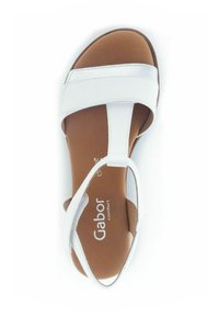 Sandale blanche avec des larges lanières, un design en T et une semelle en cuir marron. Finition texturée sur les lanières avec un détail logo visible.