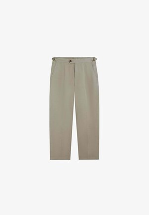 Pantalones beige a medida con pliegues delanteros, bolsillos laterales, cierre con botones y hebillas laterales ajustables en la cintura.