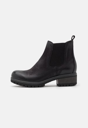 Bottine noire en cuir avec panneau latéral élastique, languette à l'arrière, talon bas empilé et semelle avec crampons pour une bonne adhérence.