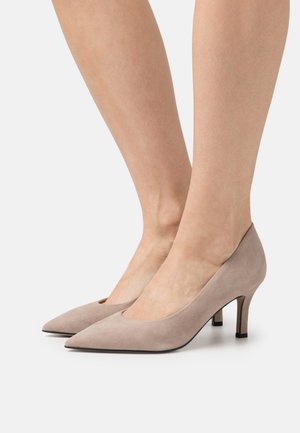 Beige suède hoge hakken met een puntige neus en een klein uitsnijdetail, met een slanke hak en een gladde textuur.