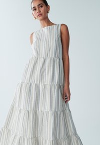 Gelaagde maxi-jurk van lichte stof, met verticale blauwe strepen. Mouwloos ontwerp met een aansluitend lijfje en een vloeiende rok.