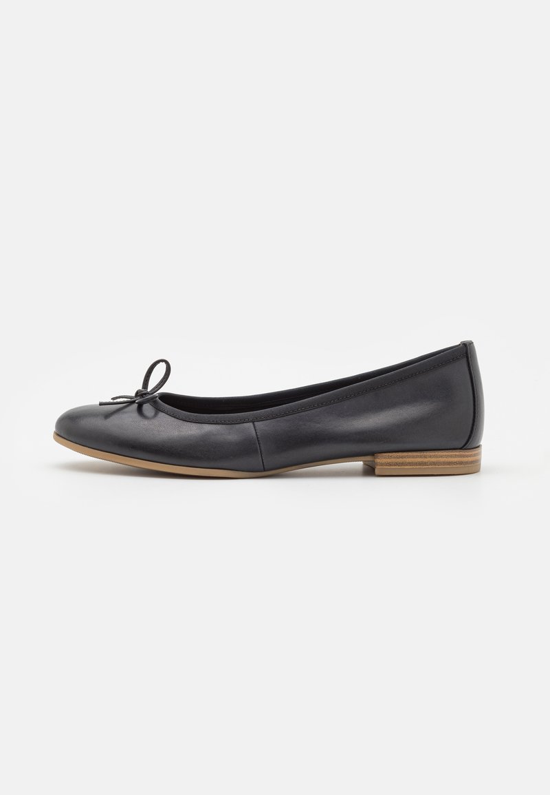 Bailarinas de cuero negro con puntera redondeada, pequeño lazo decorativo y tacón bajo de madera. Textura suave con un acabado pulido.