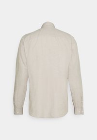 Chemise beige à manches longues boutonnée, vue de dos avec col et poignets boutonnés sur fond blanc uni.