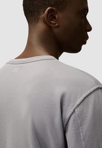 Grijze t-shirt met korte mouwen en een ronde hals, met een gestikte vierkante detail op de achterkant en een soepele stofstructuur.