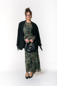 Grønn og svart mønstret kjole med lange ermer, lagd under en svart blazer. Svart håndtak med teksturert overflate og spisse svarte hæler.