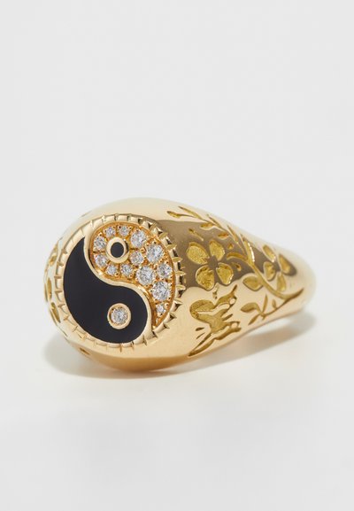 Goldring mit einem Yin-Yang-Design, verziert mit schwarzem Emaille und funkelnden Steinen, welche mit floralen Gravuren am Ringband geschmückt sind.