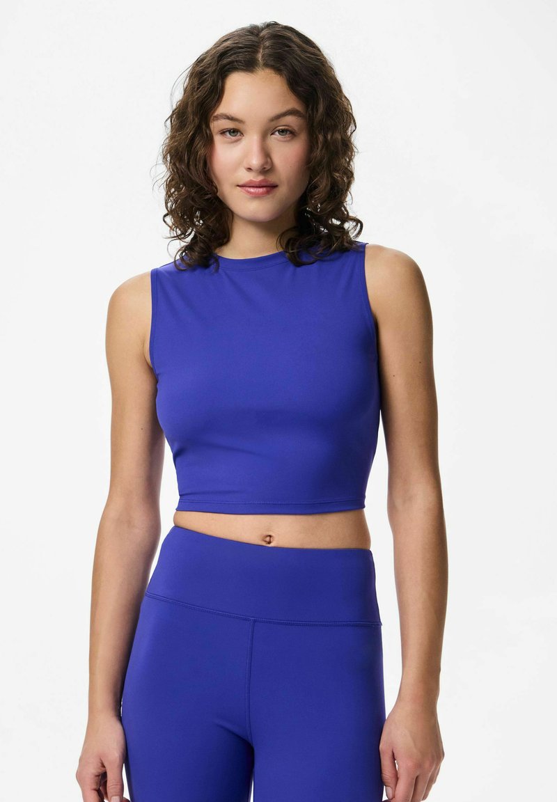 Kraljevsko plava sportska crop majica s okruglim izrezom i bez rukava, u kombinaciji s odgovarajućim tajicama, izrađena od glatkog, rastezljivog materijala.