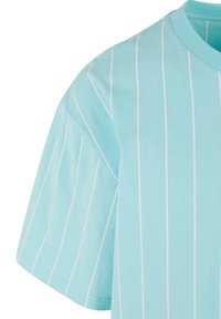 T-shirt bleu clair à manches courtes en coton, avec des rayures blanches verticales et un col rond.