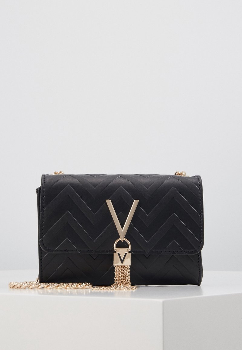 Bolso de mano de patrón de chevron negro con herrajes dorados, que presenta un destacado logo en forma de V y una correa de cadena, acabado texturizado, forma rectangular compacta.