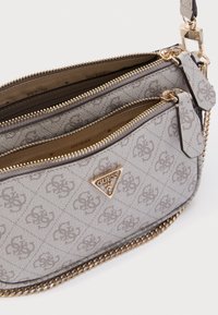 Borsa in tessuto grigio con doppio scomparto con cerniera, dettagli in catena dorata e un emblema triangolare con logo. Presenta motivi sottili e una texture.