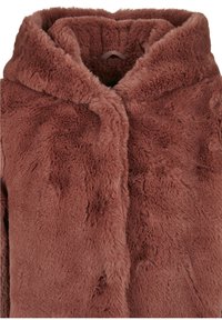 Manteau en fausse fourrure de couleur rouille chaude, avec une surface texturée, une grande capuche et une sensation douce et moelleuse. Aucune fermeture ou ornement visible.
