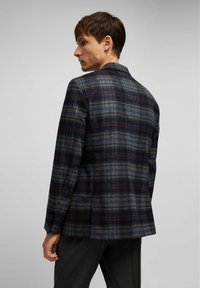 Wollen blazer in een donker ruitpatroon met blauwtinten, grijs en bordeauxrood. Heeft een gestructureerde kraag en een enkele knoopsluiting.