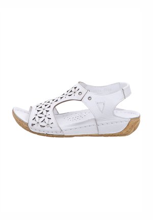 White leather sandals with cut-out floral design, open toe, adjustable back strap, and a textured beige cork sole.