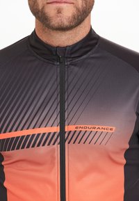 Mannen fietsshirt in een vervaagd zwart en oranje, met diagonale strepen, een volledige rits en het "ENDURANCE" logo op de borst.