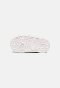 White athletic shoe outsole with circular tread pattern and textured sections. Features a logo embossed on the side and rounded edge.