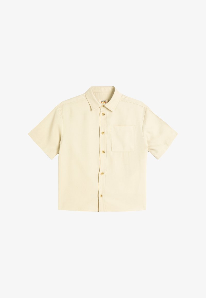 Kortærmet skjorte i lys beige, lavet af bomuld. Har en knaplukning foran, en spids krave og en enkelt brystlomme.