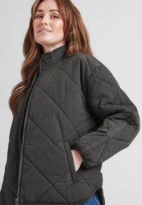 Quilted lightweight jacket in dark gray, featuring a stand-up collar, side pockets, and elastic cuffs. Smooth fabric with subtle sheen.