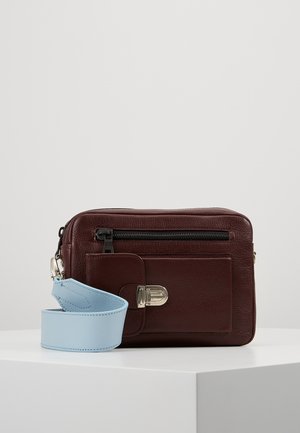 Dark brown leather crossbody bag with front zip pocket, silver clasp, and wide detachable light blue strap, displayed on white surface.