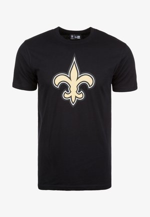 Camiseta de algodón negra con un gran logo de color crema de flor de lis en el frente. Diseño de mangas cortas y cuello redondo.