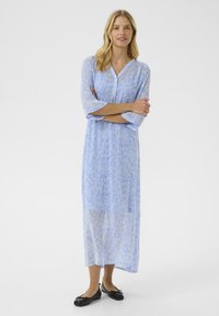 Light blue, long-sleeve dress with a floral pattern, v-neck, and knee-length. Paired with black flat shoes. Gentle texture and flowy design.