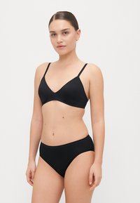 Czarny zestaw bikini z trójkątnym biustonoszem na cienkich ramiączkach oraz dopasowanymi majtkami typu hipster, wykonany z gładkiego, elastycznego materiału.