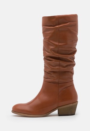 Bottes en cuir marron montantes au design décontracté, à bout arrondi, avec un talon en bois bas et une texture lisse.