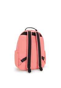 Zaino rosa chiaro con accessori neri, cinturini regolabili e tasche laterali; texture trapuntata e forma arrotondata con manico superiore.