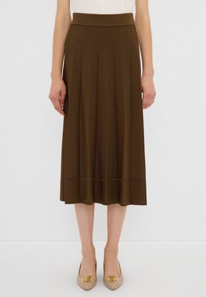 Gonna midi plissettata marrone con una cintura larga e dettagli di cucitura orizzontale all'orlo, abbinata a scarpe beige con accenti dorati.