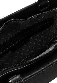 Interior de una bolsa de cuero negro con un compartimento con cremallera. Forrada con una tela negra texturizada con rayas diagonales grises.
