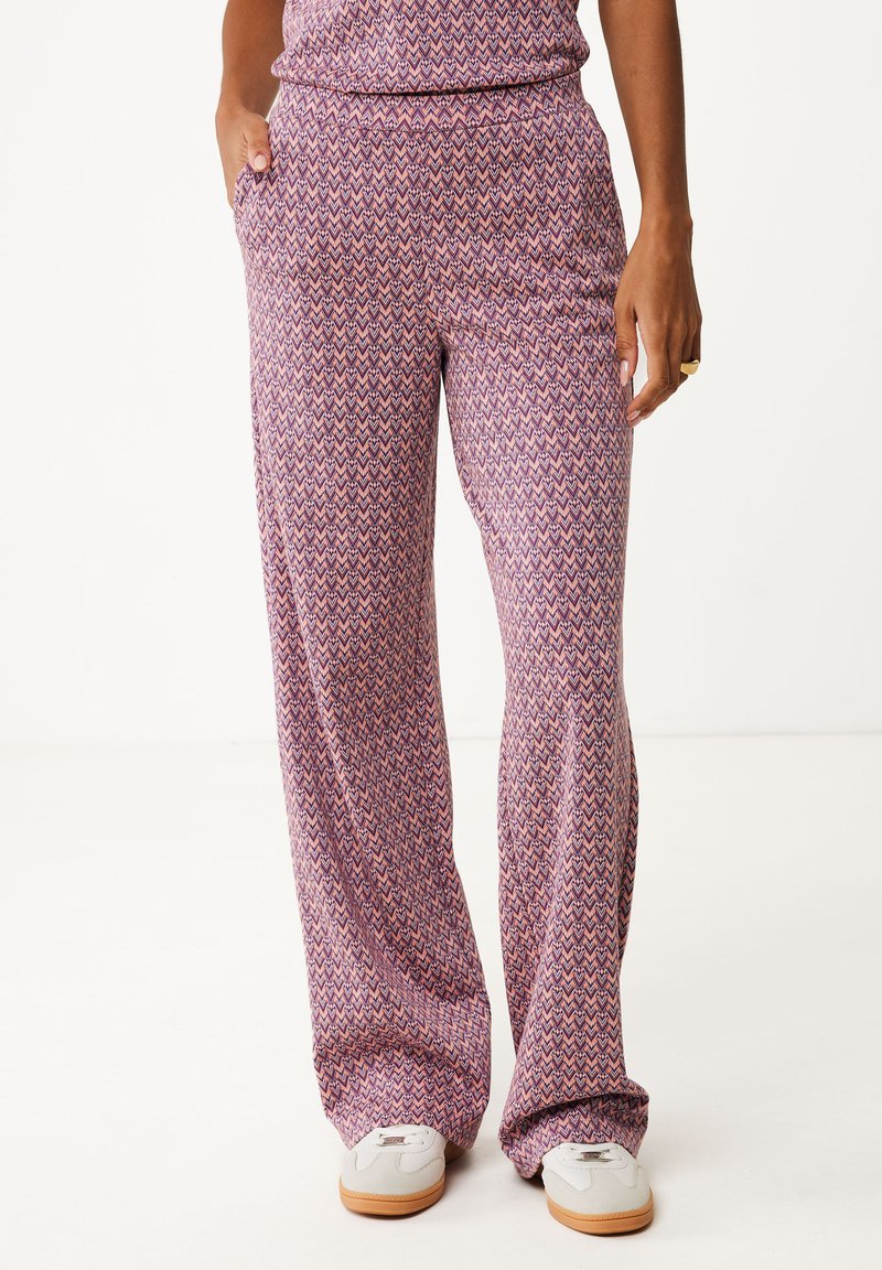 Pantalons larges à motifs violets avec un design en zigzag, dotés de poches latérales et d'une taille élastique, associés à des baskets blanches.