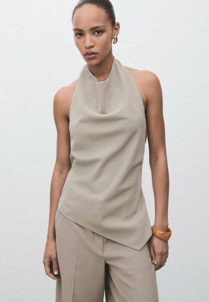 Beige sleeveless top with a draped neckline, paired with matching loose trousers. Features smooth, soft fabric and a subtle asymmetric design.