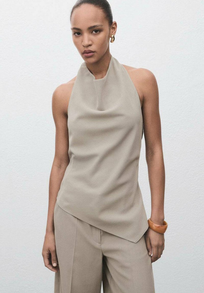 Haut sans manches beige avec un décolleté drapé, associé à un pantalon ample assorti. Présente un tissu lisse et doux avec un design asymétrique subtil.