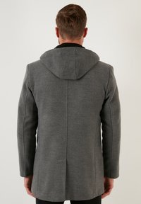 Abrigo de lana gris con capucha, que presenta una textura suave, un diseño elegante y un corte recto. Detalles de costura notables a lo largo de la parte posterior.