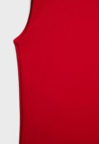 Haut rouge sans manches en tissu de coton lisse. Présente une coupe ajustée avec des bords nets et une texture minimale.