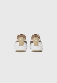 White and beige sneakers with a textured upper, padded collar, and contrasting brown accents. Features white rubber sole with patterned tread.