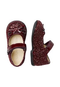 Chaussures Mary Jane en paillettes bordeaux avec une finition brillante, ornées d'un nœud et d'une fermeture à sangle, sur une semelle en caoutchouc noir.