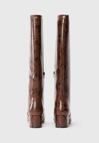 Brown knee-high boots with black snake skin pattern, block heels, and side zippers, shown standing upright on a white background.