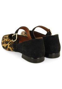 Zapatos planos de ante negro y estampado de leopardo con una correa en el tobillo y un tacón negro brillante. Textura suave y diseño de punta redondeada.