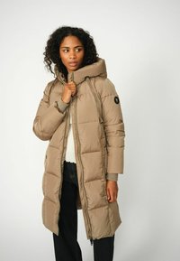 Pufferjas in beige, met een hoge kraag en capuchon, ritssluiting en geribbelde manchetten. Kenmerkend gestikt ontwerp met logo op de mouw.