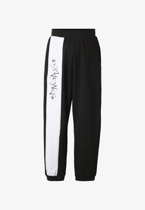 Sorte joggingbukser med en bred hvid lodret stribe på venstre ben med graffiti-stil "DNGAS" tekst og stjerneaccents.