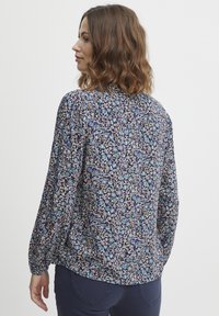 Kukkakuvioinen pitkähiha blouse tummansinisessä värissä, jossa on monivärinen printti. Kevyt kangas, rento malli ja kootut hihat joustavilla hihansuilla.