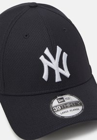 Schwarze Baseballmütze aus strukturiertem Stoff. Mit weißem, gesticktem "NY"-Logo. Verstellbare Größe mit einem runden Etikett, das die Größe angibt.
