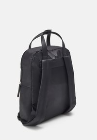 Sac à dos en nylon noir avec deux poignées en tissu, une fermeture éclair et un dos rembourré. Texture lisse, design minimaliste et sans logos visibles.